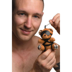 Man holding Master Series bound teddy bear keychain by its silver split ring, small portable size