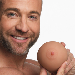 Man holding the Mistress breast masturbator globe, showing textured areola detail and pink nipple