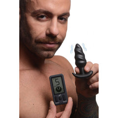 Man using LCD remote to adjust vibration settings on Bang! black swirl butt plug
