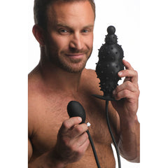 Master Series Ass Puffer inflatable silicone anal plug held by male model with pump bulb