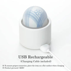 MIZU vibrator in holder with USB charging cable connected at the base