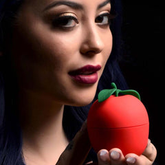 Model holding closed red Forbidden Apple silicone stimulator, palm-sized scale reference