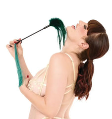 Model holding the green feather tickler close to her face, showing the soft feather end in use