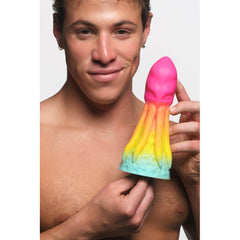 Model holding King Kraken silicone dildo showing rainbow pink-yellow-teal colour gradient