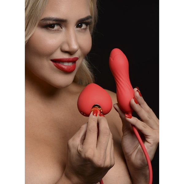 Model holding Shegasm red silicone heart-shaped stimulator and textured vibrating egg near face