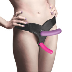 Model wearing black harness with purple and pink Triple Peg silicone dildos in double-penetration position