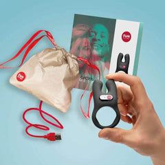 NŌS cock ring with charging cable and branded kraft pouch on blue background, full kit view