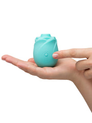 One hand cradling ROMP Rose Glow with fingertip near power button showing small portable size