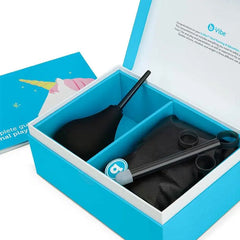 Open b-Vibe gift box revealing enema bulb, lube launcher, storage pouch, and accessories in teal interior
