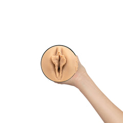 Close-up overhead view of skin-tone vaginal opening on stroker sleeve held up by a hand