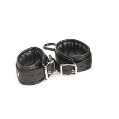 Close-up of padded black vegan leather wrist cuffs with silver buckle hardware included
