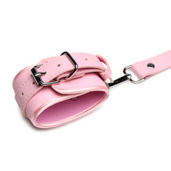 Close-up of padded pink wrist cuff showing adjustable buckle and silver snap connector