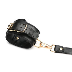 Padded wrist cuff with gold buckle and gold lobster-clasp connector on white background
