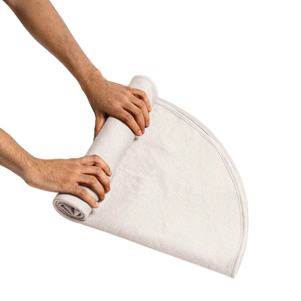 Pair of hands rolling the round Dame Throw, demonstrating its compact and portable design