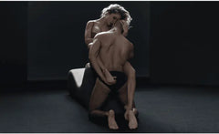 Partners embracing beside the Cello Chaise, one supported by the curved foam bolster end