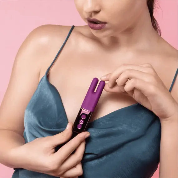 Person in blue satin top holding Le Wand Deux vibrator, demonstrating discreet compact size