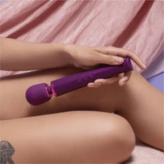Person holding Le Wand Petite purple massager while seated, showing handheld scale and grip