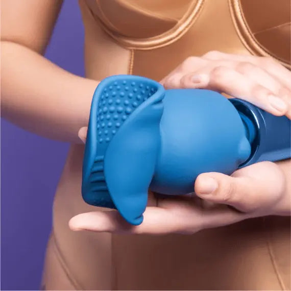 Person holding Le Wand Stroke attachment against wand head, showing flexible silicone wings in use