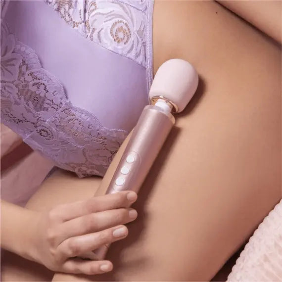Person in lavender lace lingerie holding Le Wand Petite Massager against hip area