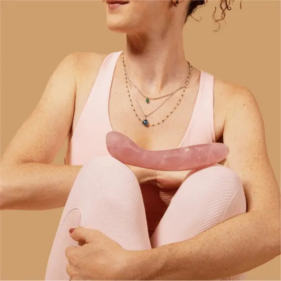 Person in pink activewear cradling the Le Wand Crystal G Wand against their body