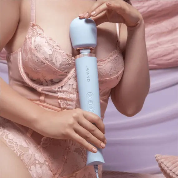 Person in pink lace lingerie holding Le Wand sky blue massager against upper body for relaxation