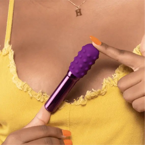 Person in yellow top holding Grand Bullet vibrator, demonstrating its lightweight handheld size