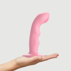 Pink Wave M dildo balanced on an open palm to illustrate its compact medium size