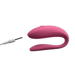 Pink We-Vibe Sync Lite couple's vibrator with magnetic charging cable connected to charging port