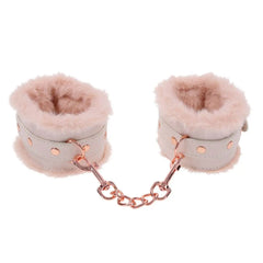 Close-up of plush fur-lined wrist cuffs connected by a rose gold chain for comfort
