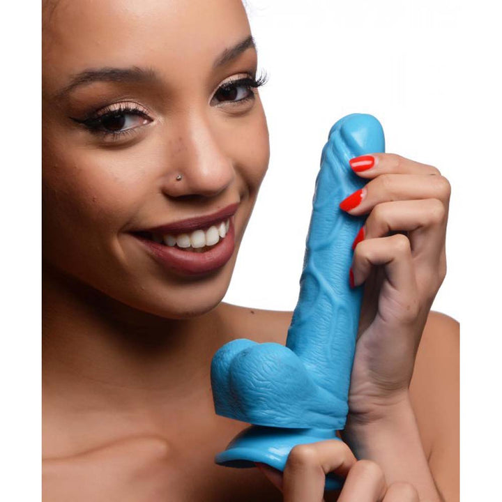 Pop Peckers 6.5-inch blue silicone dildo with balls held up by smiling model