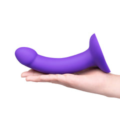Purple curved silicone dildo resting in open palm to illustrate size and gentle upward curve