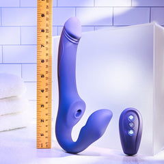 Purple strapless strap-on beside a ruler showing approximately 9 inches total length with remote