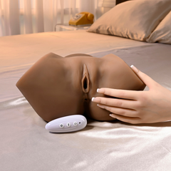 Realistic stroker on satin sheets with a hand resting on it and remote control visible