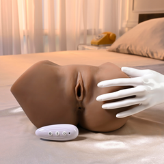 Realistic stroker with wireless remote beside it and a gloved hand demonstrating scale