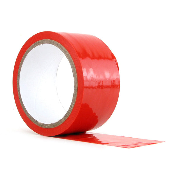 Red bondage tape unrolled slightly from cardboard core, showing smooth, flexible red film material