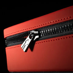 Close-up of red faux-leather zip case with black metal zipper pull and red stitching detail