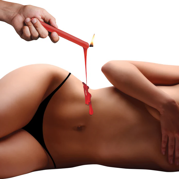 Red paraffin drip candle held over a person's lower back, melted wax dripping for wax play sensation