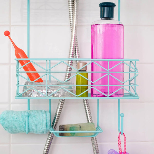 Red ROMP Pop waterproof vibrator resting on a teal shower caddy beside bath products