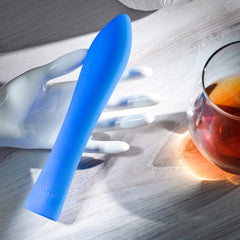 Robust Rumbler vibrator resting on table beside glass, highlighting flexible curved body