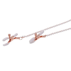 Close-up of rose gold alligator-style nipple clamps with white silicone tips and bead chain