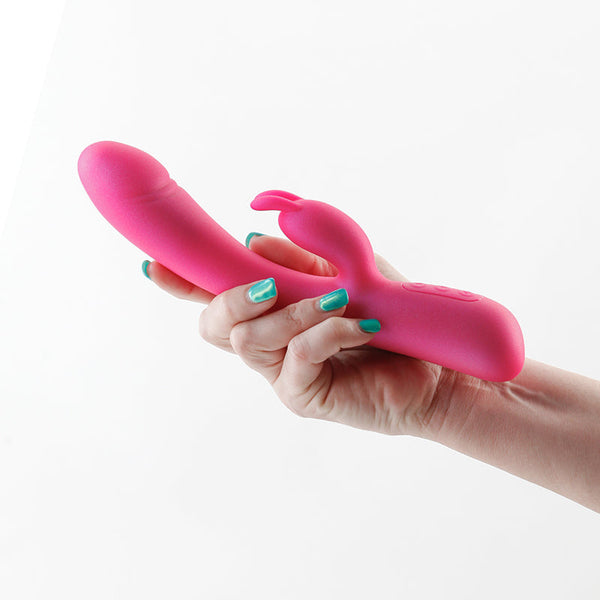 Royals Divine rabbit vibrator in metallic pink held in a hand, showing dual-stimulation silhouette