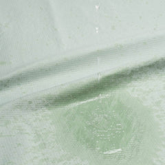 Close-up of sage fabric surface with water droplets beading up, showing waterproof barrier layer