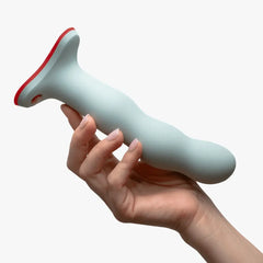 Sage green BOUNCER dildo held in one hand, showing flared red-trimmed base and smooth silicone body
