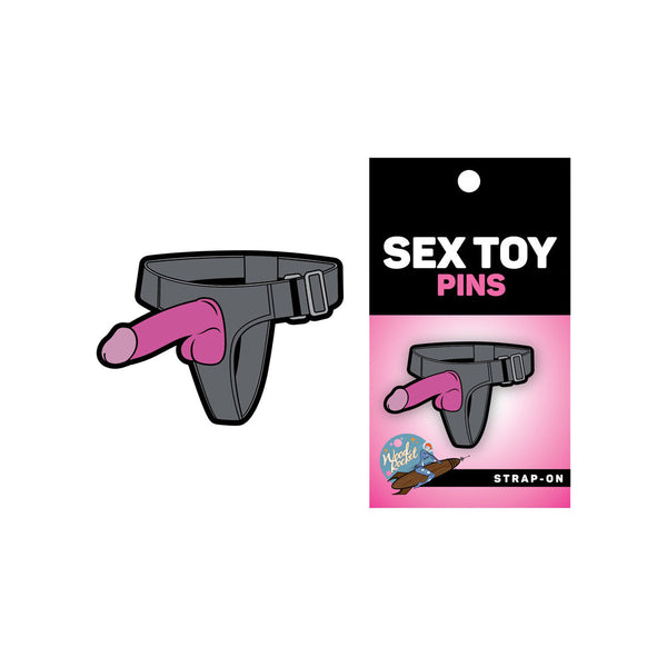 Sex Toy Pins strap-on pin shown beside its black and pink retail card packaging