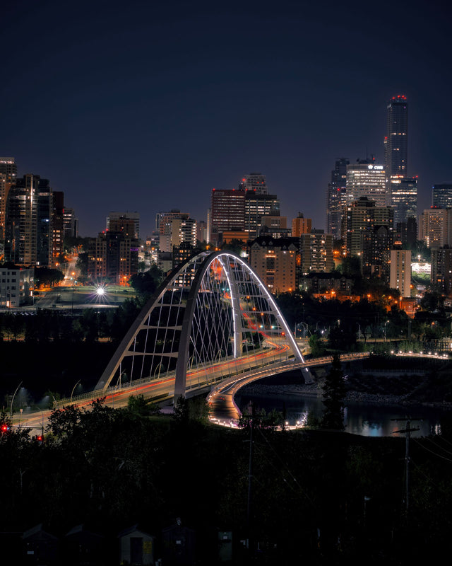 The Walterdale Bridge lit up at night in front of the Edmonton skyline