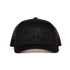 Sexy Living black trucker cap, front view showing tonal embroidered script logo on structured panel