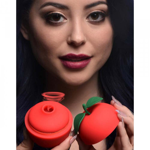 Shegasm Forbidden Apple red silicone clit stimulator shown open, held by a model