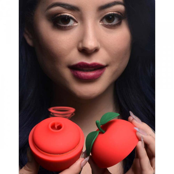 Shegasm Forbidden Apple red silicone clit stimulator shown open, held by a model