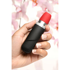 Shegasm Pocket Pucker lipstick clit stimulator held in hand against soft floral background
