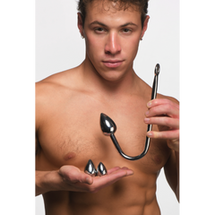 Shirtless male model holding the stainless steel anal hook and interchangeable plugs to show scale